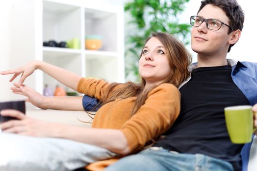 Lovely couple watching TV while drinking tea in their living room