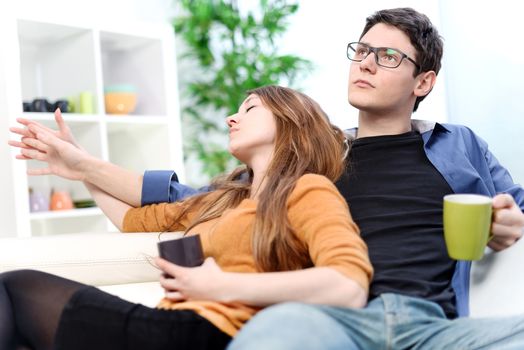 Young couple sitting and relaxing on sofa with cup in hand