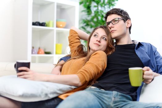 Lovely couple watching TV while drinking tea in their living room