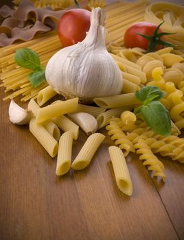 different kind of raw pasta with tomatoes garlic and basil