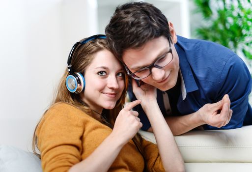 Attractive young couple listening music together in their living room at home