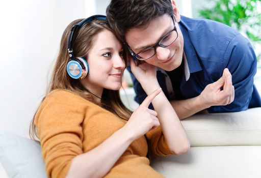 Attractive young couple listening music together in their living room at home