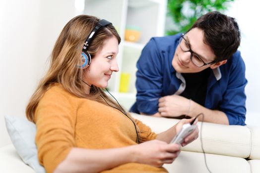 beautiful blond listening to music while her boyfriend watching her with love