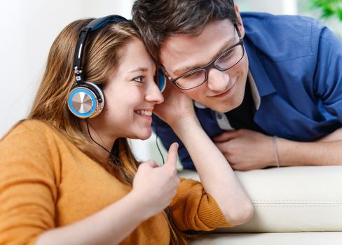 Attractive young couple listening music together in their living room at home