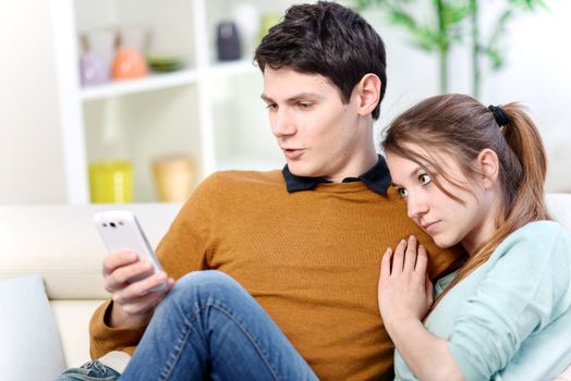 Attractive young married watching a screen of cell in living room