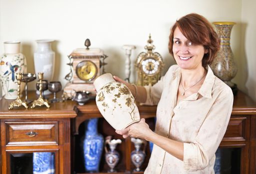 Proud woman holding vase from her collection of antiques