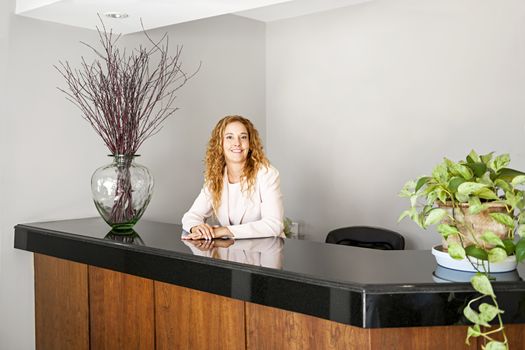 Receptionist standing at reception counter in office