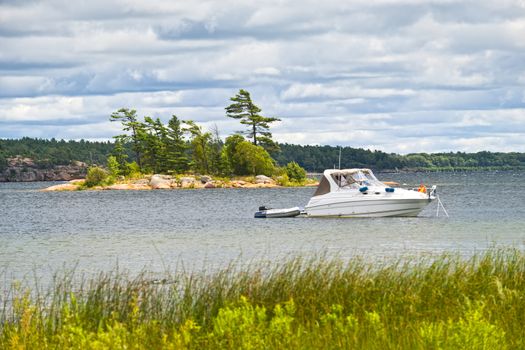 Motorboat anchored with dinghy on lake in Georgian Bay, Ontario, Canada