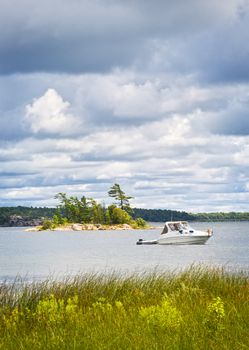 Motorboat anchored with dinghy on lake in Georgian Bay, Ontario, Canada