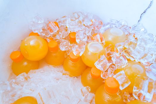 Orange juice In a bottle on the ice background.