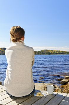 Woman sitting on dock relaxing by beautiful lake in Algonquin Park, Canada.