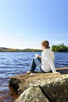 Woman relaxing by beautiful lake on sunny fall day in Algonquin Park, Canada