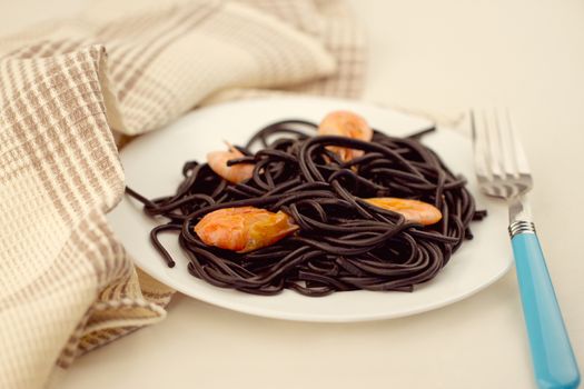 Black spaghetti with prawns on white plate