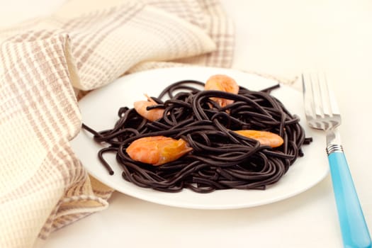 Black spaghetti with prawns on white plate