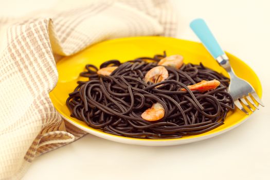 Black spaghetti with prawns on yellow plate