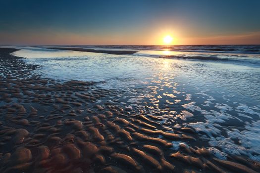 gold sunset over North sea sand beach at low tide, North Holland, Netherlands