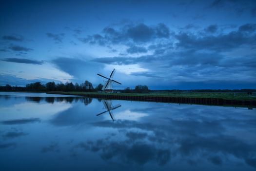 Dutch windmill by river in dusk, Holland