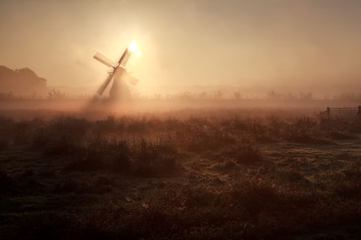 sunshine behind windmill in misty morning, Holland