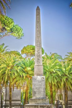 Ancient Obelisk surrounded by palms on a sunny day