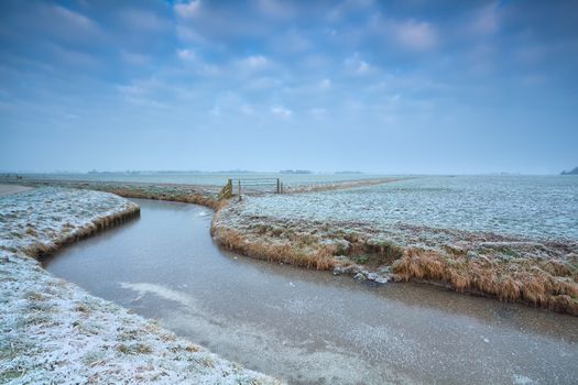 frozen canal on Dutch farmland in winter