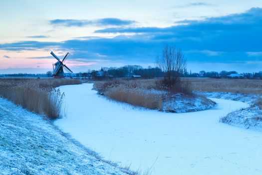 windmill and frozen river in snow, Holland