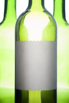 Back-lit green wine bottles with empty label for copy.