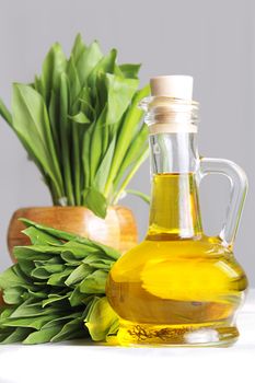 Cluster of fresh wild garlic leaves with mortar and oil