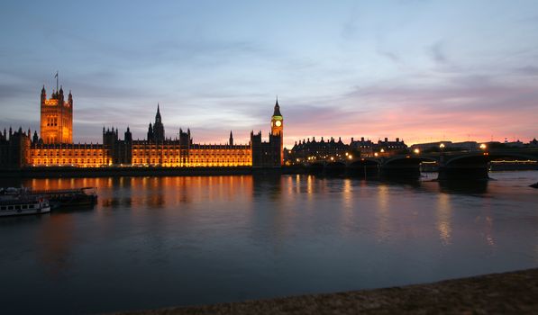 A view across the River Thames of the Houses of Parliament at sunset.