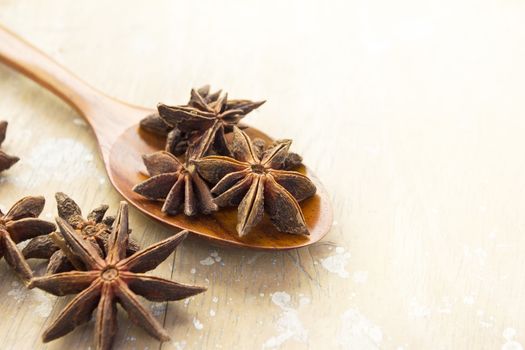Anise stars in wood spoon and on the vintage wooden surface background