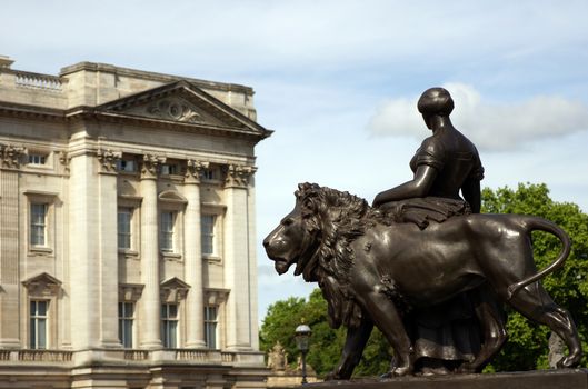 A bronze woman statue standing next to a lion statue