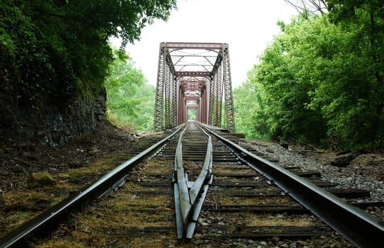 Train tracks leading to a bridge in the middle of nowhere