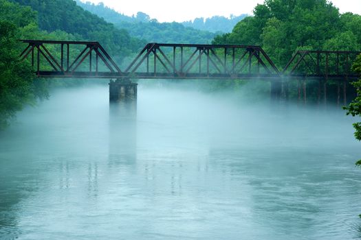 Railroad train tracks over a bridge in the fog