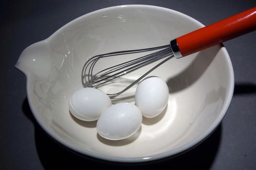 Three eggs in a mixing bowl with a wisk