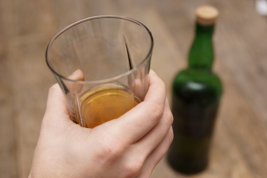 A man holding a glass of scotch next to a bottle
