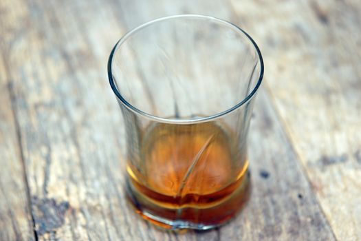 A single glass of scotch on a wooden table