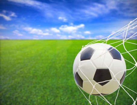 soccer ball in goal net over blue sky background 
