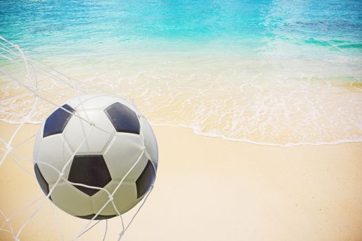 Soccer ball in a net on beach background