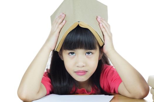 Serious school girl, tired schoolgirl studying with a pile of books and holding a book over her head 