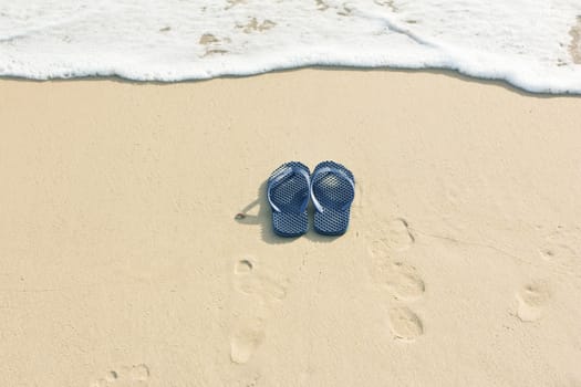 Sandals on beach and sea wave