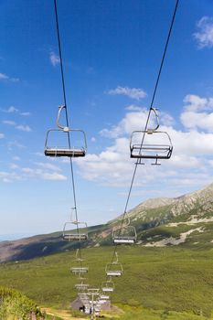 view on mountains in summer with ski lift on blue sky background