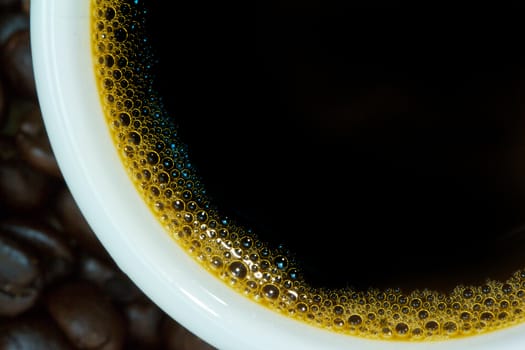 Closeup of hot coffee in white cup on coffe beans