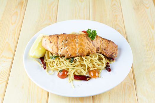 Spaghetti Salmon with chilli, tomato on white plate over wood background