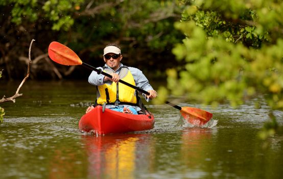 Man paddling in a red kayak in Florida