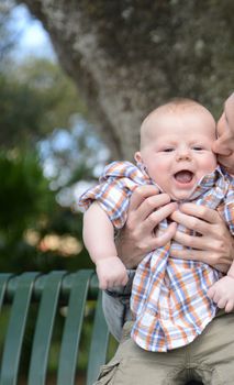 mother kissing laughing baby boy during summer