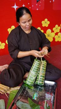 HO CHI MINH CITY, VIET NAM- JAN 15: Senior people make traditional cake for New Year occasion, the cake cover by green bananna leaf in Ho Chi Minh, Vietnam on Jan 15, 2013