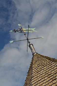 Ornate metal weather vane on a oak shingle tiled roof.