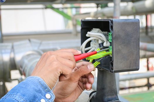 Technician use screwdriver tighten nut in junction box 