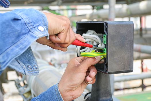 Technician use screwdriver tighten nut in junction box 