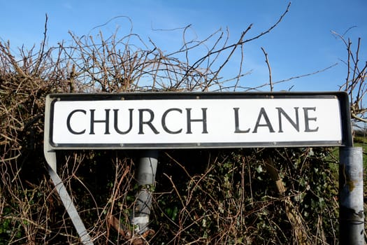 Road sign for Church Lane, a common street name, against a rural hedgerow