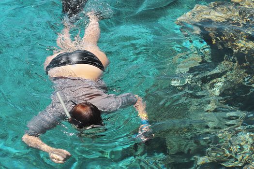 Woman photographer diving into water of Red sea